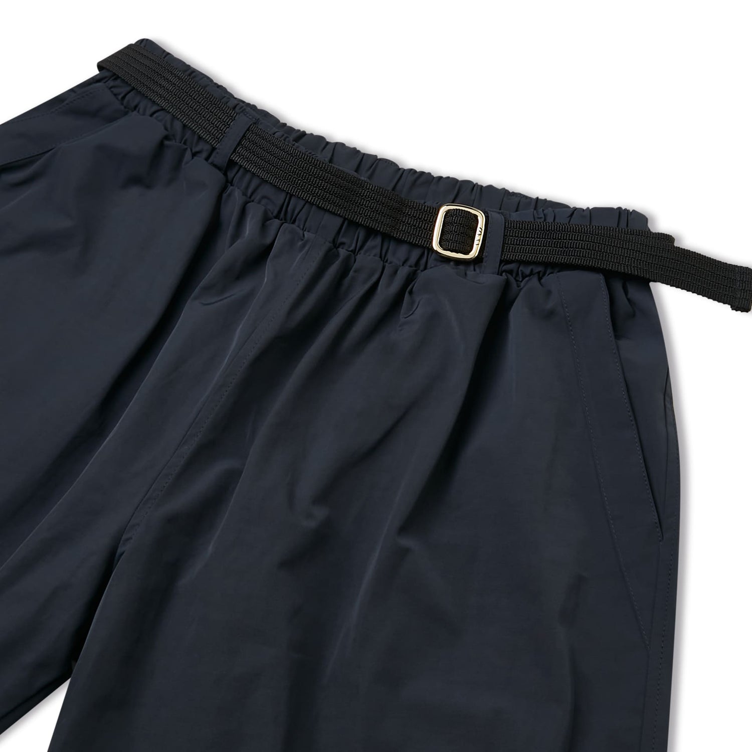 Calça marinho: detalhe do cós elástico e fivela dourada na cintura.