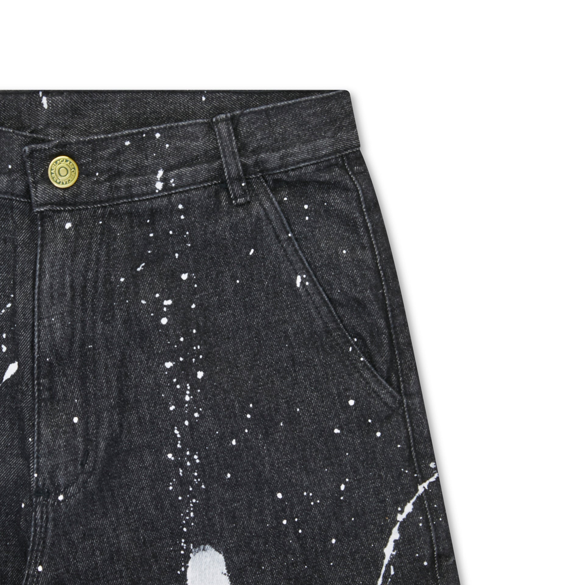 Detalhe de jeans preto com respingos brancos, cós com passante e bolso frontal.
