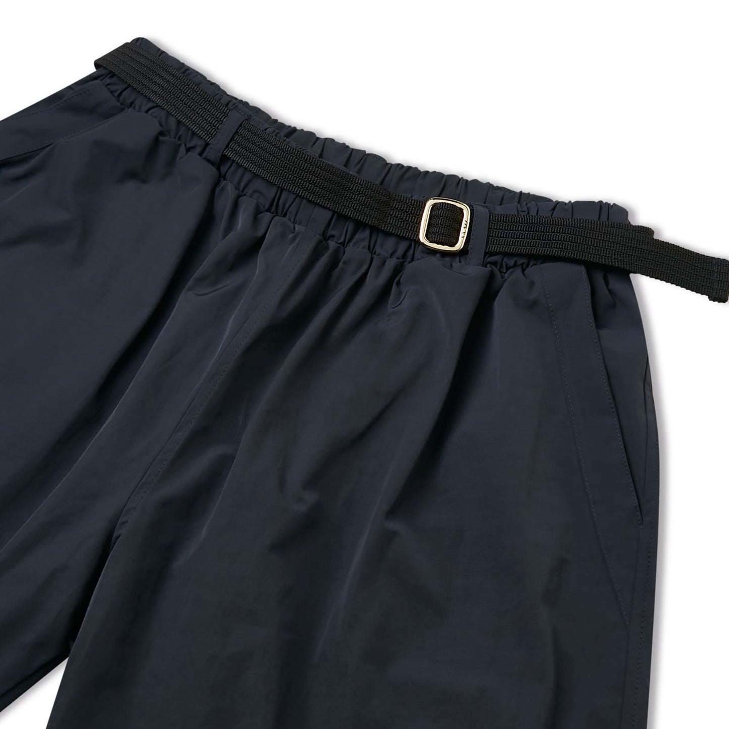 Calça marinho: detalhe do cós elástico e fivela dourada na cintura.