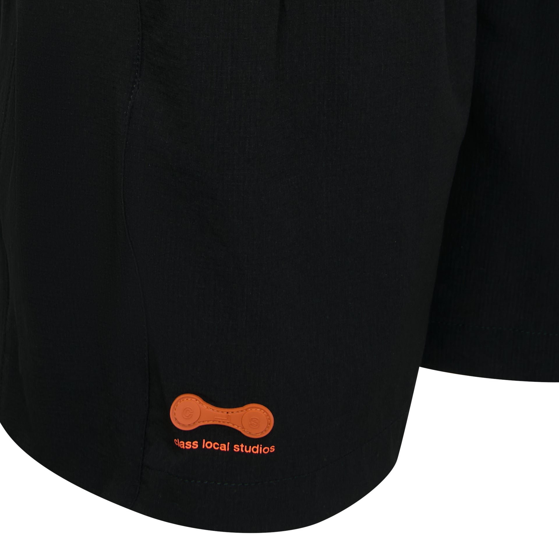 Barra de shorts preta com patch laranja e texto bordado discreto.