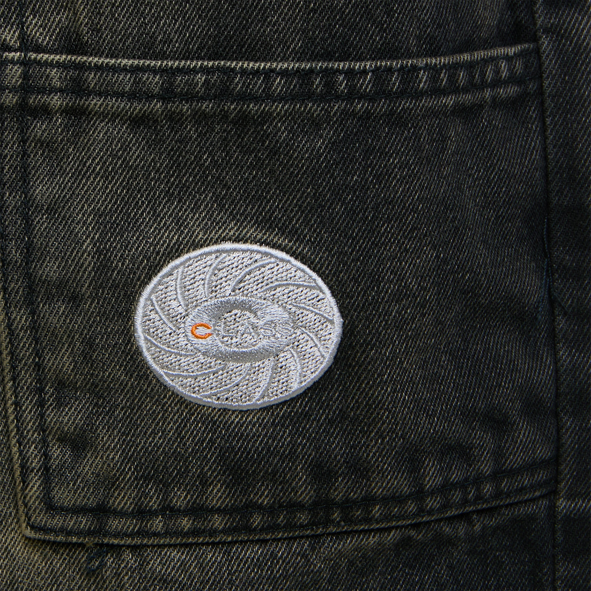 Patch oval bordado no bolso frontal da calça jeans escura