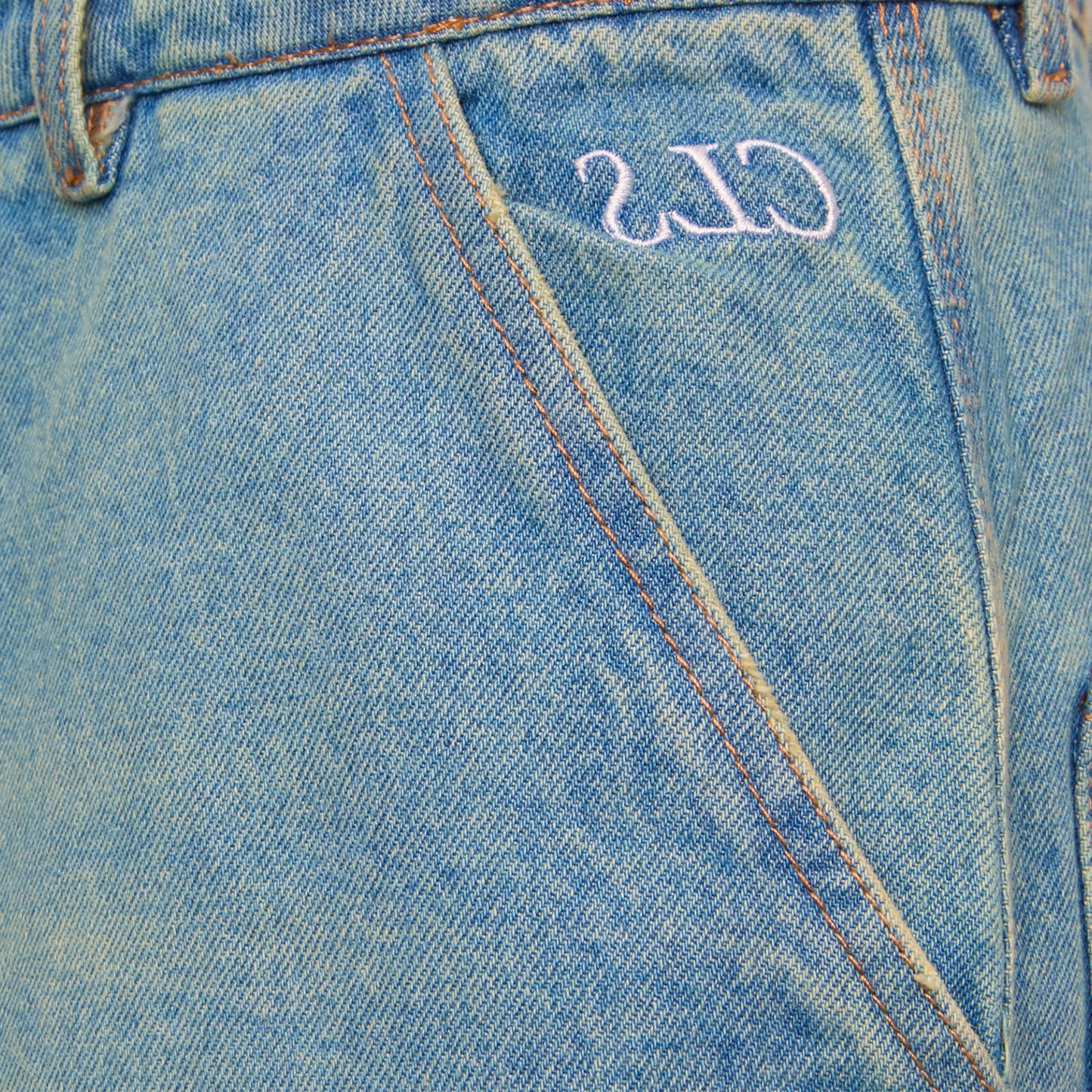 Detalhe do cós da calça jeans azul stonewash com etiqueta numérica bordada