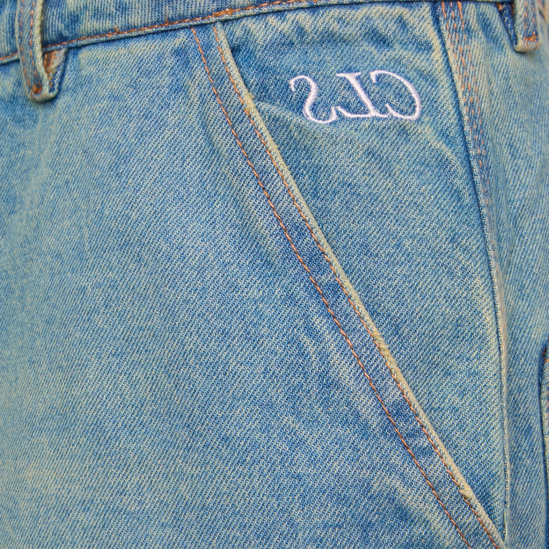 Detalhe do cós da calça jeans azul stonewash com etiqueta numérica bordada